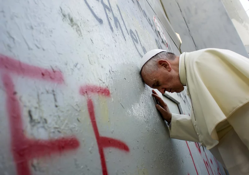 Pope Francis touches the wall that divides Israel from the West Bank, on his way to celebrate a mass in Manger Square next to the Church of the Nativity in Bethlehem.